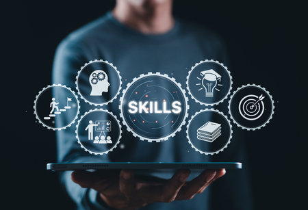 Skills Development and Professional Training Concept. Businessman holds tablet displaying gear icons with word "SKILLS," representing knowledge, growth, training, education, and personal development.の写真素材