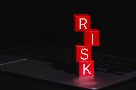 Red Risk Blocks Representing Digital Danger. Stacked red blocks spelling the word RISK placed on laptop, symbolizing digital threats, business uncertainty, data, and cybersecurity concerns.の写真素材