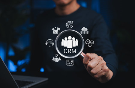 CRM Customer Relationship Management System Concept. Magnifying glass over CRM icons, symbolizing customer relationship management, data analytics, support, cloud storage, and digital marketing tools.の写真素材