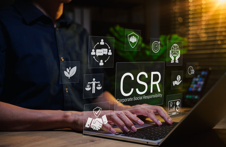 Corporate social responsibility (CSR) concept. Person using laptop with CSR icons representing...