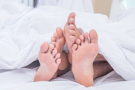 Feet of couple side by side in bedの写真素材