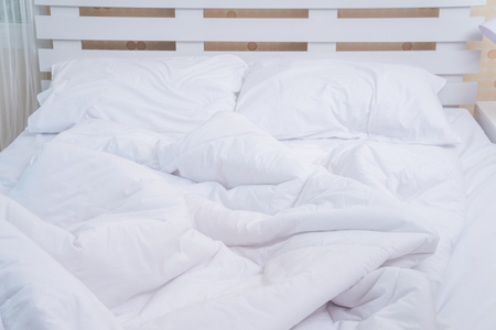 Close up white bedding sheets and pillow on wooden wall room backgroundの写真素材