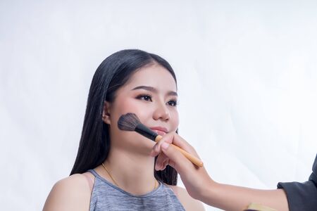 Makeup brush on the face of the woman. Beautiful woman face Perfect makeup on the color backgroundの写真素材