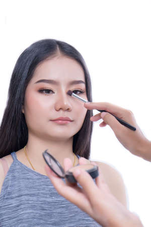 Makeup brush on the face of the woman. Beautiful woman face Perfect makeup on the color backgroundの写真素材