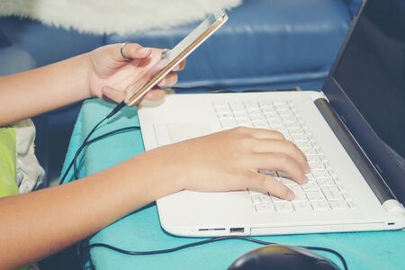 young man using laptop computer and mobile smart phone at home office to work successfully