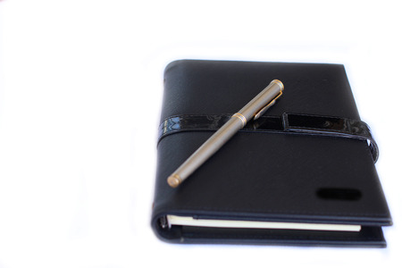 Black notebook and pen on white isolatedの写真素材