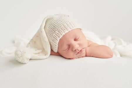 Cute newborn baby lies swaddled in a white blanket. Baby goods packaging template. Closeup portrait of newborn baby with smile on face. Healthy and medical concept.の写真素材