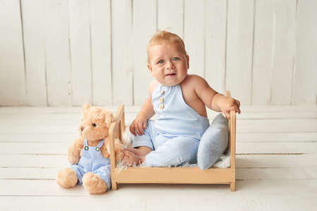 Baby boy sitting on crib. Children Protection Day. Happy childhood. Early child development. Educational toys. Mother's day card. Child plays with toys. Happy babyの写真素材