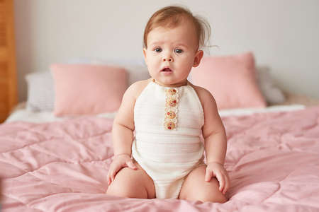 Children's Day. Sweet funny baby on bed in children room. Greeting card, copyspace for your text....
