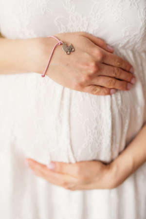 Pregnant woman holds hands on belly. Pregnancy, maternity, preparation and expectation concept....