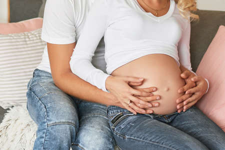 Pregnant couple expecting baby. Pregnant woman holds hands on belly. Pregnancy, maternity,...