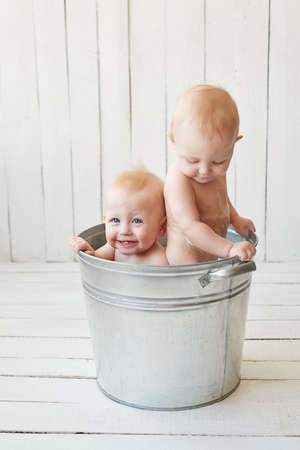Kids hygiene. Shampoo, hair treatment and soap for children. Kid bathing in large tub. Twin boys wash, infant hygiene, health and skin care. Baby in bath. Children's Dayの写真素材