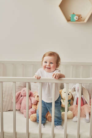 Children's Day. Sweet funny baby in children room. Scandi style girl room. Child play with educational toys. Early child development. Kids room with toys. Mother's Day greeting card.の写真素材
