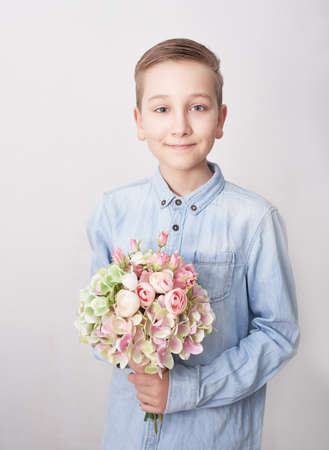 Child boy with bouquet of flowers. Mother's Day Greeting Card. Happy mothers day frame background. Spring card template. Happy Birthday or Valentine. Women's Day. Copy space. Child gives bouquet.の写真素材