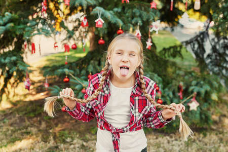 Family Christmas in July. Portrait of girl near christmas tree. Baby decorating pine. Winter holidays and people concept. Merry Christmas and Happy Holidays Greeting card. Christmas child.の写真素材