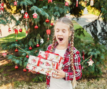 Family Christmas in July. Portrait of girl near christmas tree with gifts. Baby decorating pine. Winter holidays and people concept. Merry Christmas and Happy Holidays Greeting card. Christmas child.の写真素材