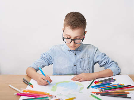 Child boy draws planet for earth day. Protection of enviroment, Mother Earth Day greeting and...