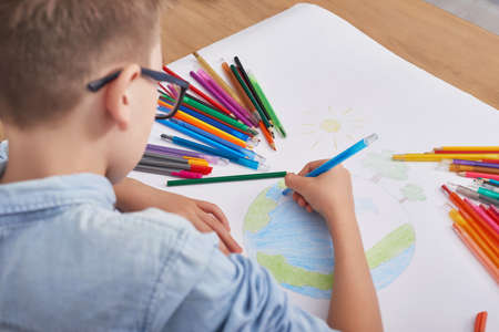 Child boy draws planet for earth day. Protection of enviroment, Mother Earth Day greeting and...