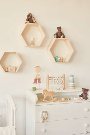 Kids room scandinavia. Wooden toys in children's room, chest of drawers and white bed, interior of children's bedroom. Loft style nursery. Neutral design of children's bedroomの写真素材
