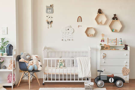 Kids room scandinavia. Wooden toys in children's room, chest of drawers and white bed, interior of...