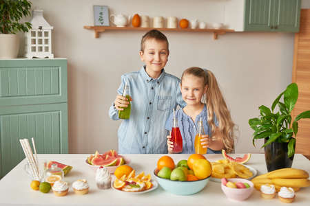 Children eat fruit pineapple, watermelon, apples and drink drinks with chia. Healthy food in the children's menu. Happy children with fruits and fresh juice in kitchen, kids healthy eating conceptの写真素材