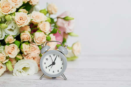 Cozy morning. Mothers day greeting flower card. Bouquet of flowers and alarm clock. Good morning. Creative breakfast for Woman day. Copy space. Easter spring still life scene. Coffee mug. Time concept.の写真素材