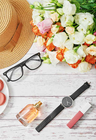 Bouquet of flowers on table. Cup of tea or coffee and macaroons. Greeting card for mothers day. Happy Birthday. Glasses and watch. Flowers composition for Valentine. Cosmetics perfume and lipstick.の写真素材