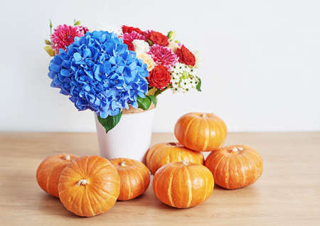 Autumn harvest pumpkin background. Pumpkins and flowers on table. Thanksgiving table. Copy space. Halloween or seasonal autumnal. Design mock up. Greeting card. Fall kitchenの写真素材