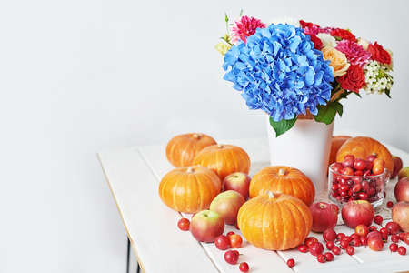 Autumn harvest pumpkin background. Pumpkins, apples and flowers on table. Thanksgiving table. Copy space. Halloween or seasonal autumnal. Design mock up. Greeting card. Fall kitchenの写真素材