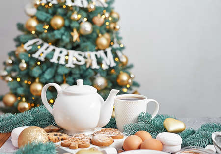 Christmas table setting. Treats and food. Tea set and sweets on background of Christmas tree. Christmastime celebration. Winter Holidays. Xmas mock up. Greeting card templateの写真素材