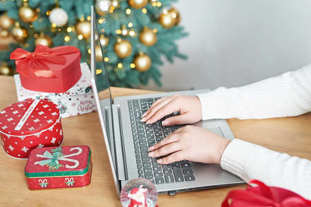 Christmas online shopping. Female buyer makes order on laptop. Woman buy presents, prepare to xmas,...