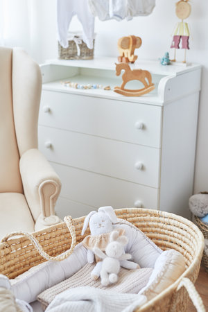 Stylish baby room interior with white armchair, wicker basket and toysの写真素材
