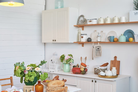 interior of white kitchen with wooden cupboards and shelves with foodの写真素材