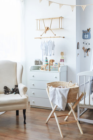 Stylish scandinavian baby room with white armchair, wooden crib and toysの写真素材