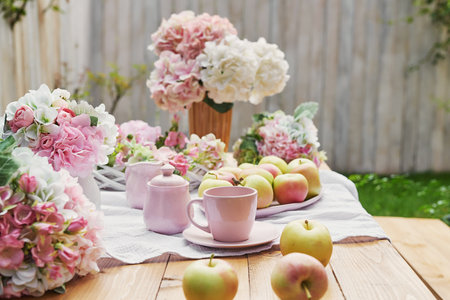 Cup of tea and fresh apples with hydrangea flowers on wooden tableの写真素材