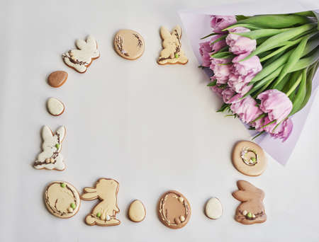 Easter composition with sweet bread, gingerbread rabbits and eggs, bouquet of flowers tulip. Holidays breakfast. Traditional easter gingerbread cookies. Easter Greeting Card Template.の写真素材