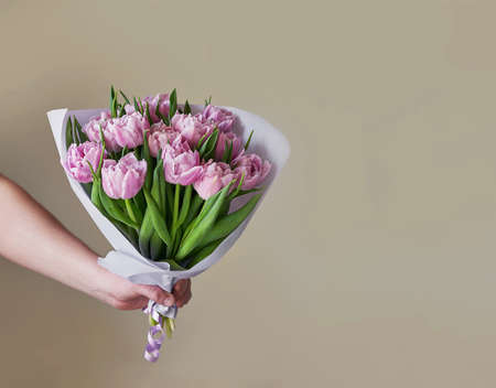 Bouquet of flowers pink tulips in hand. flower delivery. Happy Birthday! spring background. mother's dayの写真素材