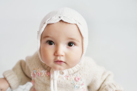 Cute baby girl in knitted clothes and hat with teddy bear toy. Children Protection Day. ...