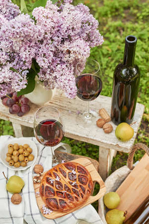 Summer picnic in the garden. Wine, pie, fruits and flowers. still life. Easter lunch and table.の写真素材