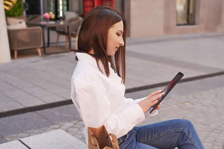 Young beautiful woman in the city. Portrait of girl on street with tablet.