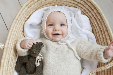 Baby in wicker cradle with wooden toy. mother's day. Children Protection Day. Cheerful child, happy childhood.の写真素材