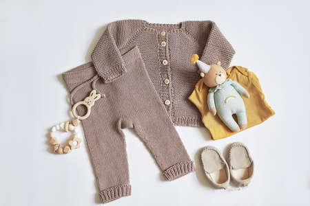 Children's knitwear. Jumper, hat, boots, socks. Wooden teether, nipple. baby shower party. Preparing for childbirth. flat layの写真素材