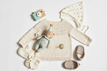 Children's knitwear. Jumper, hat, boots, socks. Wooden teether, nipple. baby shower party. Preparing for childbirth. flat layの写真素材