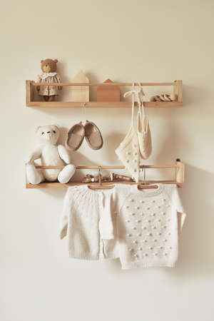Children's knitted clothes on hanger. Jacket, jumper, hat, shoes. toys. Children's room, nursery.の写真素材
