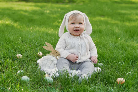 Easter Bunny baby boy. Egg hunting. Cute child in hat with ears and eggs on grass.の写真素材