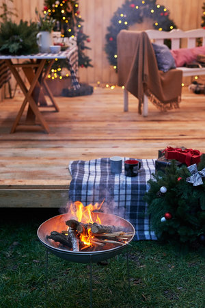 New Year and Christmas backyard decorations. Christmas tree, wreath and gifts. Winter holidays and celebrations. Bonfire and fire. Christmas barbecue.の写真素材
