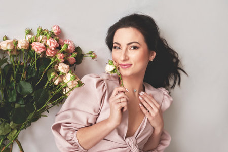 portrait of a beautiful brunette woman in a pink dress with a bouquet of flowers