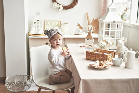 Cute little boy sitting at the kitchen table and eating cookies.