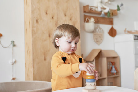 Baby child plays with wooden toys pyramid. early development.