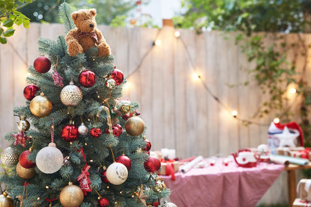 Decorated Christmas tree with teddy bear and garland on blurred backgroundの写真素材